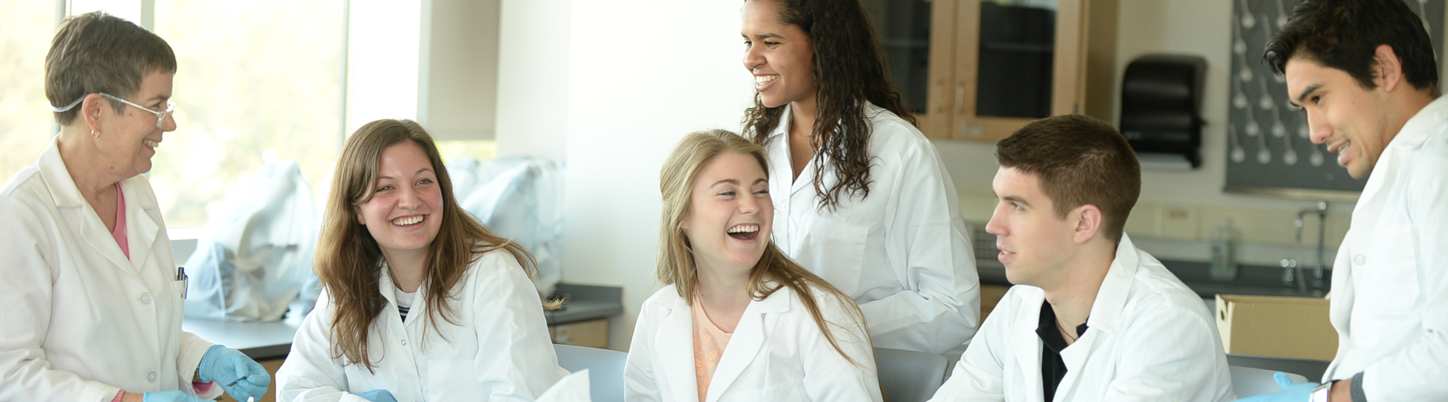 Group of students doing lab work with professor