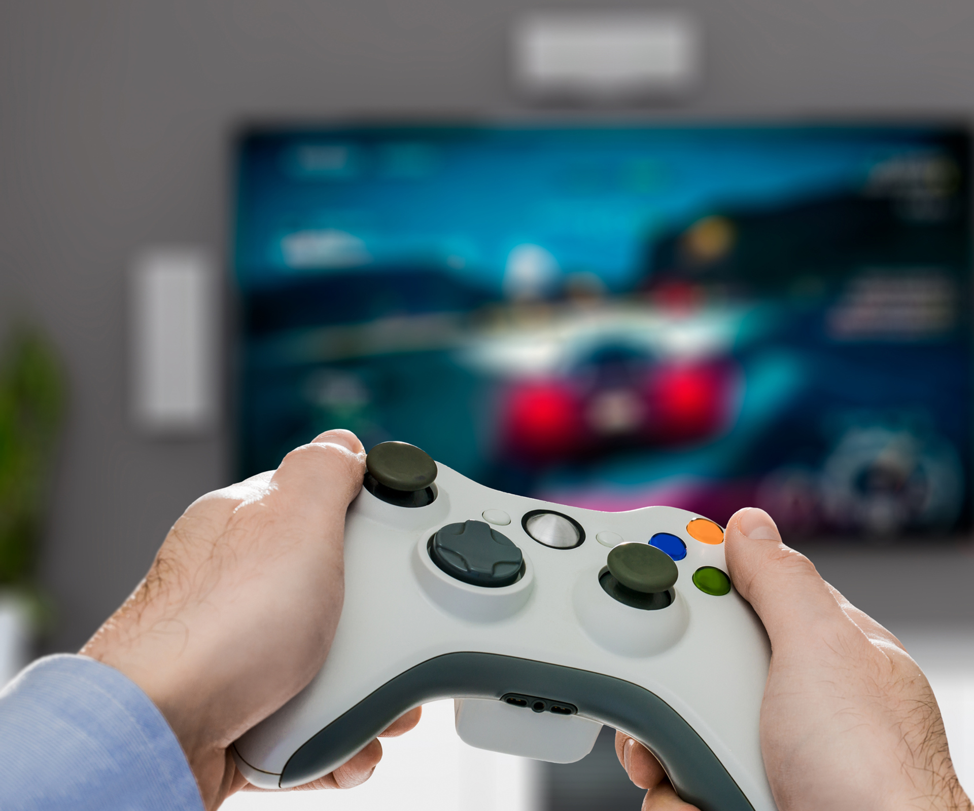 Hands holding controller in front of racing game