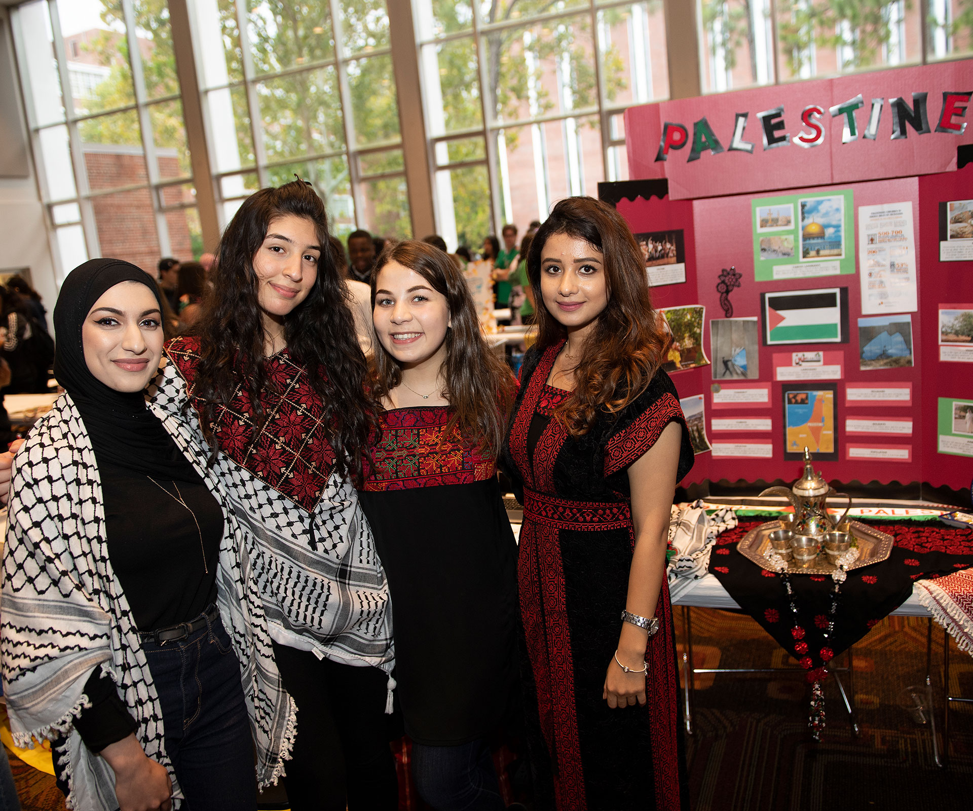 4 people standing in front of a Palestine poster