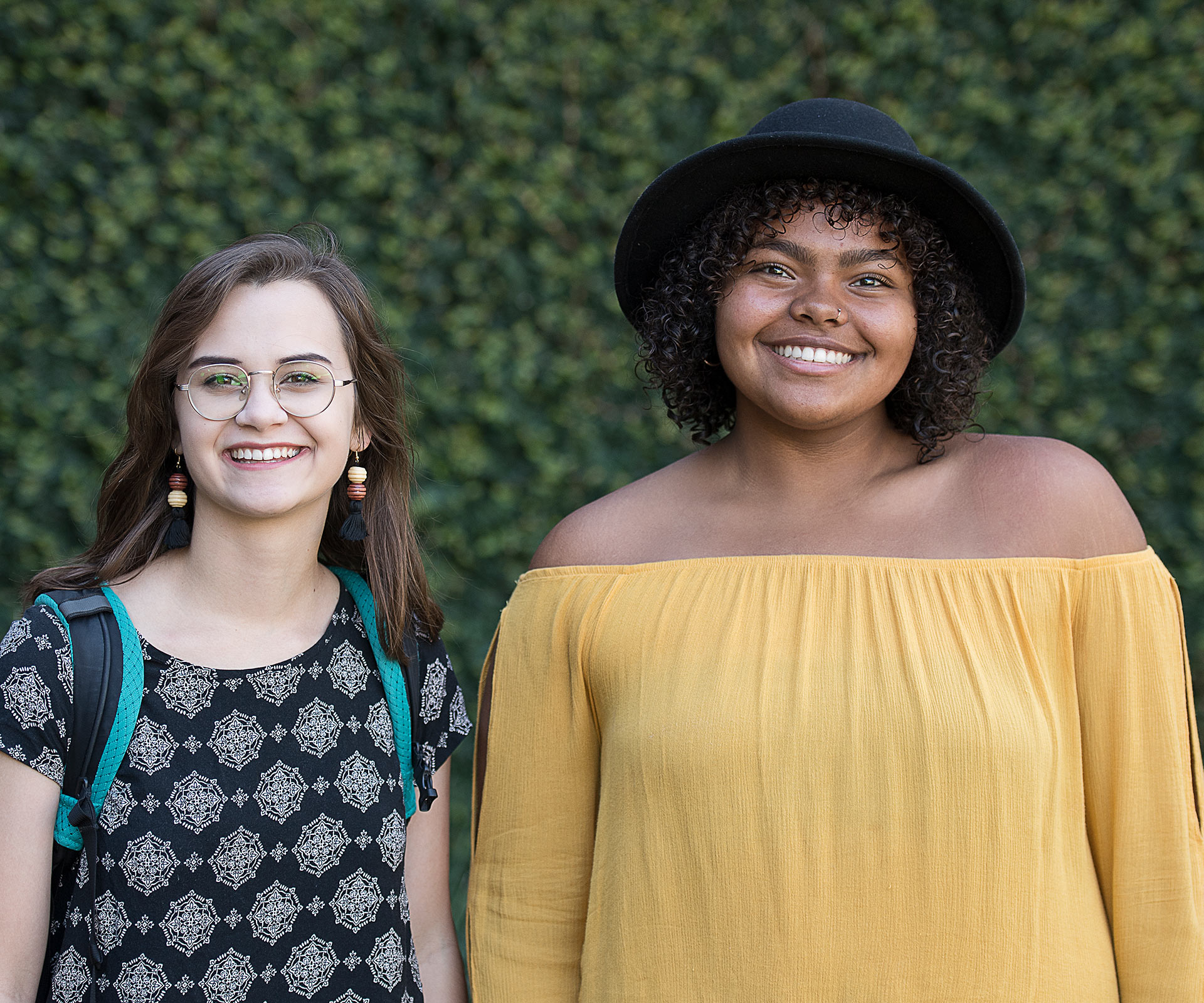 Two students standing against foliage