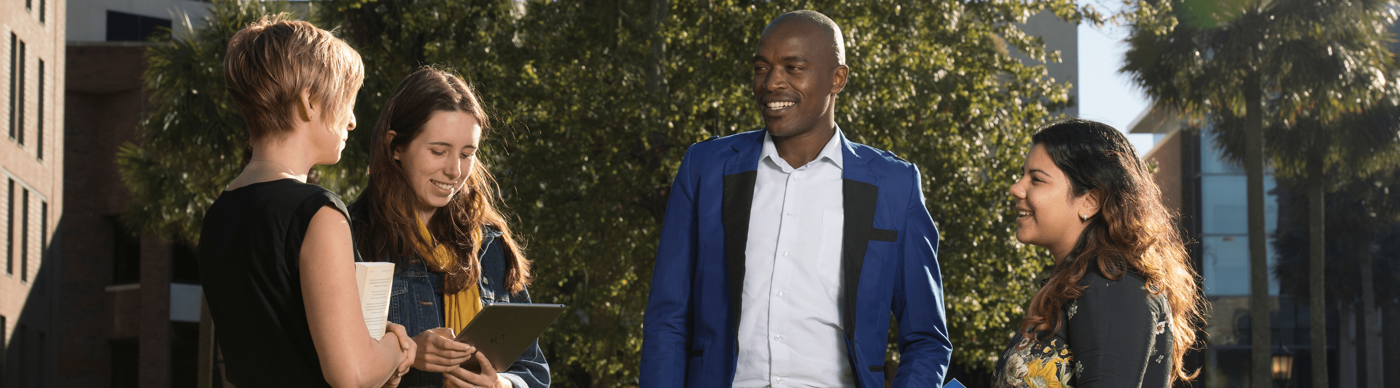 online master of business administration and pastoral studies students having a discussion outdoors.